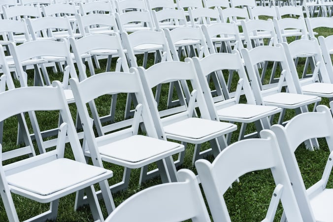 Symmetry of love Rows of white folding chairs on lawn before a wedding ceremony in summer